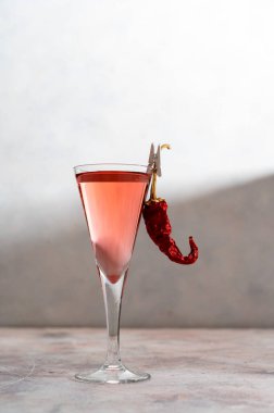 Red, hot chili pepper and vodka or liquor in glass on bright background.