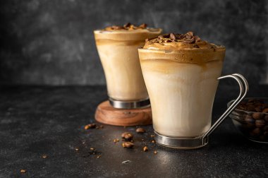 Dalgona coffee in glass cups. Dark moody backgroung with copy space.