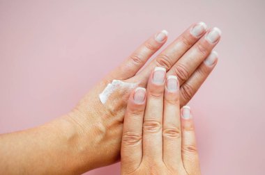 Doğal sağlıklı tırnakları olan bir kadın eli. Güzellik, el ve cilt bakımı kavramı. Pembe arkaplan.