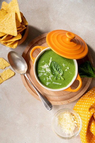 Green creamy soup. Spinach soup in orange bowl. Lifestyle food photo scene, Delicious vegan foods, copy space