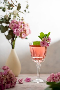 Pink drink cocktails, liquor or gin. Pink sangria fruity wine with hydrangea pink flowers. Bright, girly background.