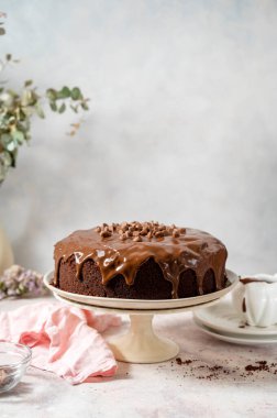 Beyaz pasta standında ev yapımı çikolatalı pasta çikolata kaplı, parlak bir arka planı var.