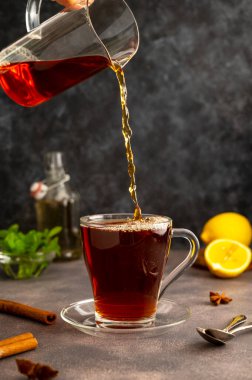 Cam çay bardağına çay doldurmak, sabah çayını limon ve naneli taze siyah çay içmek. Koyu arkaplan