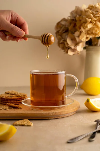 お茶に蜂蜜を入れる レモンと紅茶のグラスカップ 暖かい中性の背景 — ストック写真