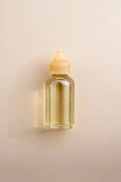 Beauty oil product bottle, essential oil bottle on warm, neutral background. Top view. Cosmetic product