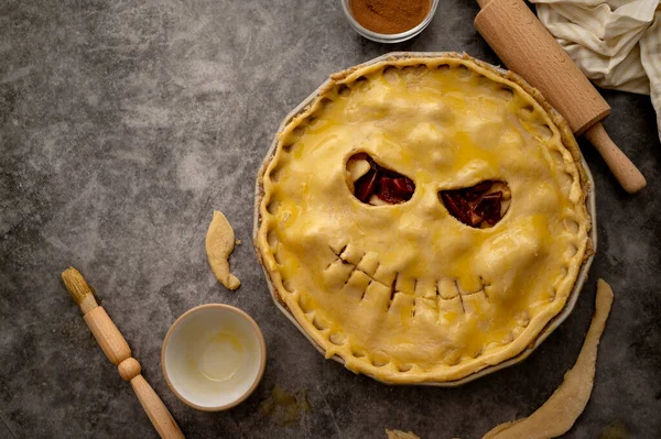ハロウィンアップルパイを調理 生の生地でカットカボチャの顔 秋のベーキングコンセプト トップビュー — ストック写真
