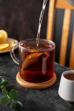 Cam bardakta siyah çay, sabah sıcak içkisi. Çay poşeti. Yaşam tarzı, karamsar fotoğraf.