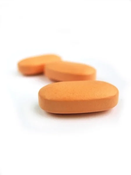 Beyaz arka planda turuncu vitamini hapları — Stok fotoğraf