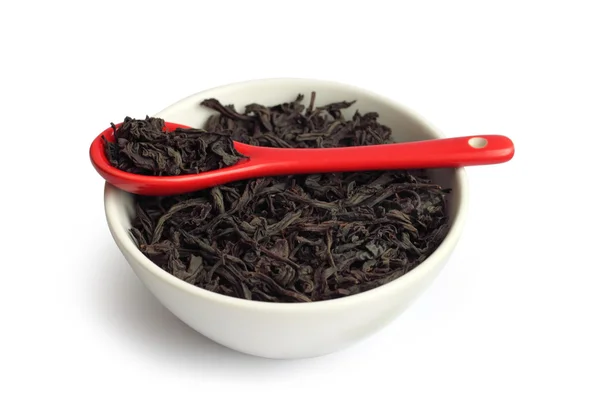 Droge zwart blad thee in een kom met rode lepel — Stockfoto
