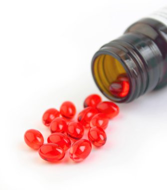 kahverengi şişe beyaz zemin üzerine kırmızı vitamin hapı