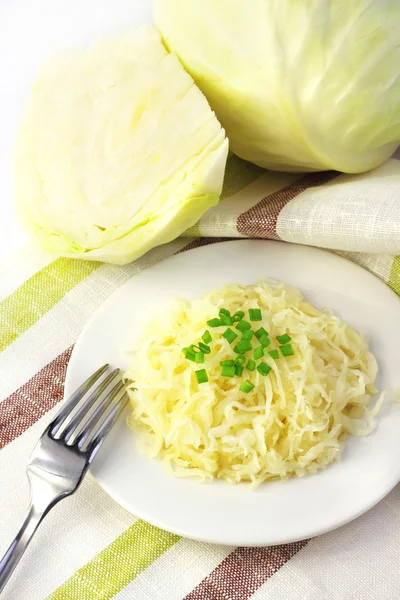 Sauerkraut on white plate and head of white cabbage — Stock Photo, Image