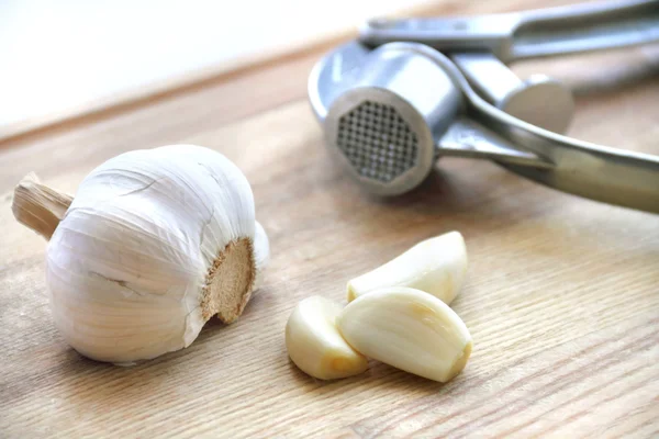 Česnek a česnek stiskněte na dřevěné prkénko — Stock fotografie