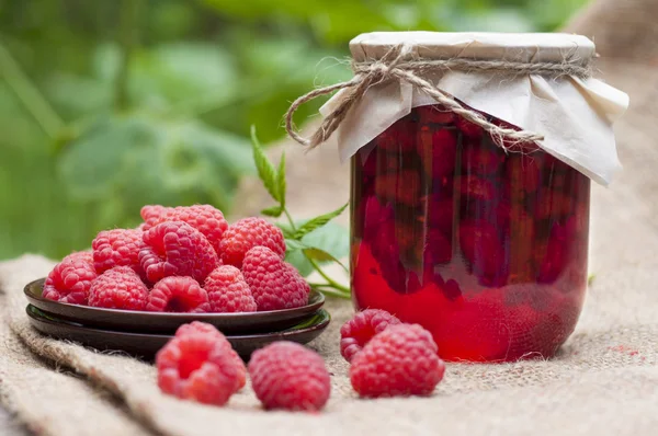 Raspberry preserve in glass jar and fresh raspberries on a plate — Stock Photo, Image