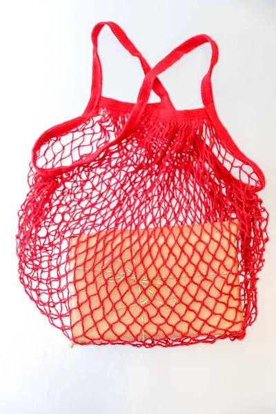 Concept of zero waste eco shopping with a red reusable mesh shopping bag 