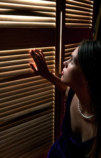 Afraid young woman sitting on floor and looking through at the grate — Stock Photo, Image