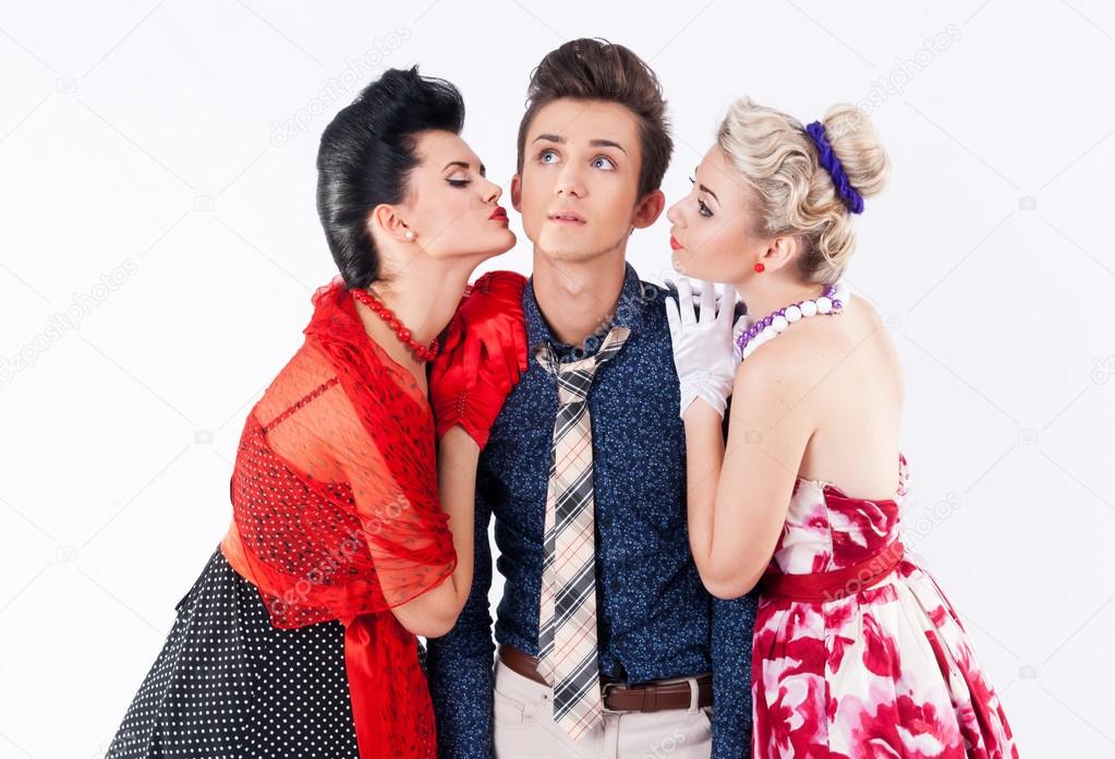 Two beautiful girls in a vintage dress kiss stylish man