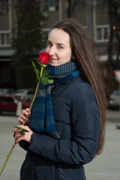 Krásná dívka s červenou růží v ruce s úsměvem — Stock fotografie