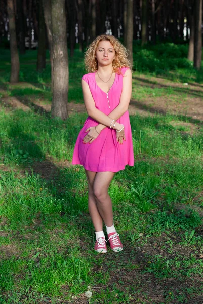 Vacker flicka på gräset i skogen — Stockfoto