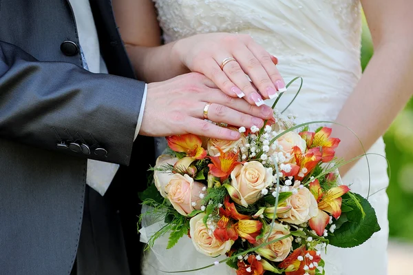 Handen en ringen op bruiloftsboeket — Stockfoto