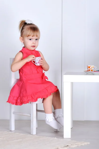 Une petite fille joue avec des poupées et des plats — Photo