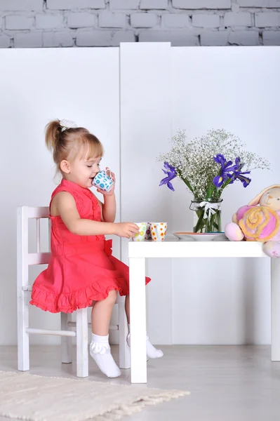 Una niña juega con muñecas y platos — Foto de Stock