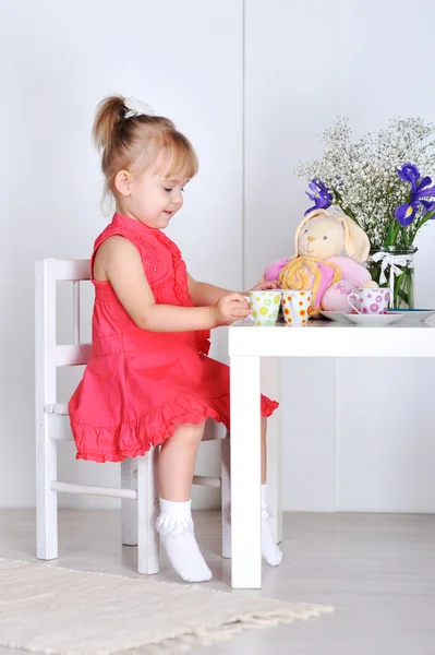 Una niña juega con muñecas y platos — Foto de Stock