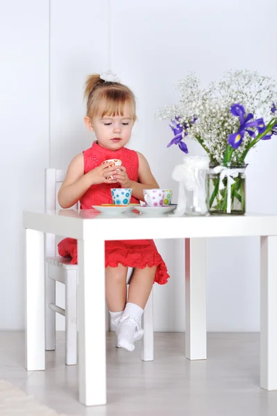 Een klein meisje speelt met poppen en gerechten — Stockfoto