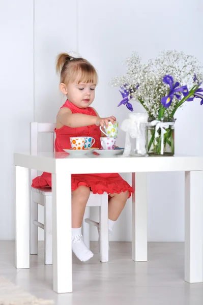 Une petite fille joue avec des poupées et des plats — Photo