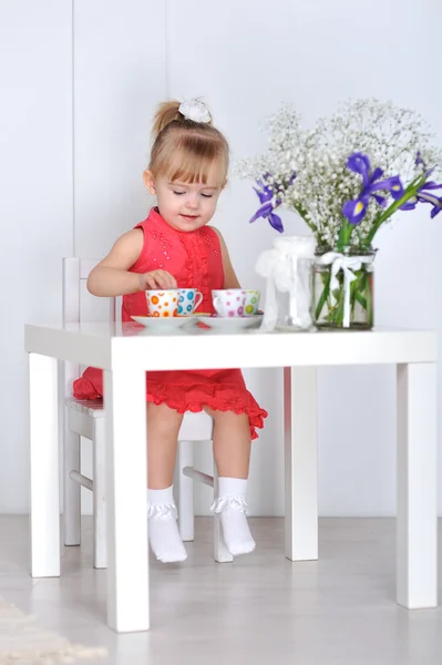 Une petite fille joue avec des poupées et des plats — Photo