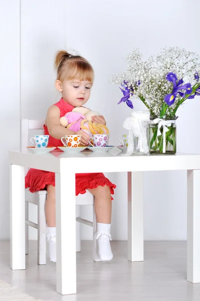 A little girl plays with dolls and dishes — Stock Photo, Image