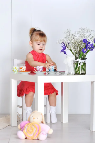 Una bambina gioca con bambole e piatti — Foto Stock