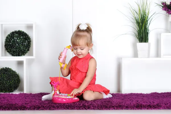 Ragazza bionda, indossa un vestito, parla al telefono giocattolo, chiama la mamma — Foto Stock