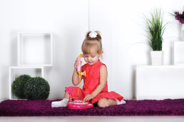Chica rubia, vistiendo un vestido, hablando en el teléfono de juguete, llamando a mamá — Foto de Stock