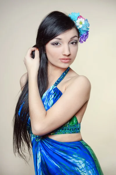 Beautiful young woman with colorful flowers in hair — Stock Photo, Image