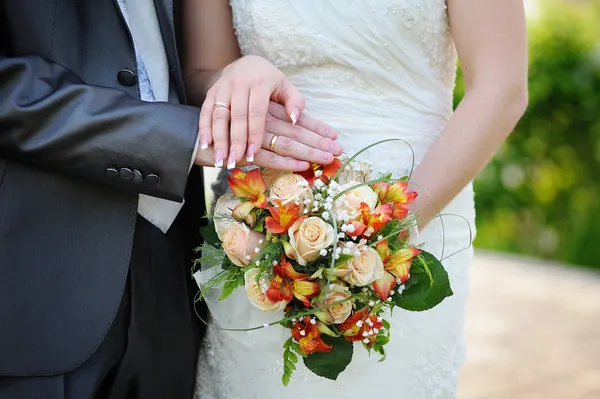 Ruce a kruhy na oranžové svatební kytice — Stock fotografie