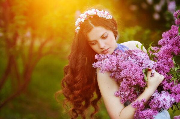 Beautiful girl with a flower lilac the sun