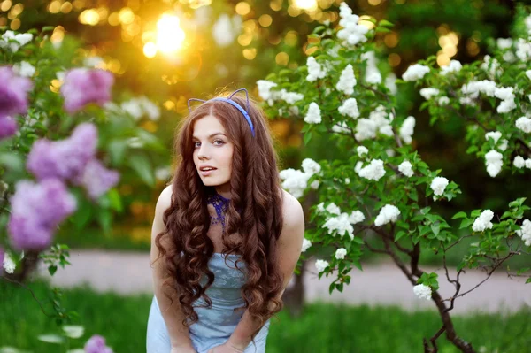 Menina bonita com uma flor lilás o sol — Fotografia de Stock