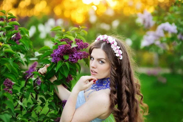 Beautiful girl with a flower lilac the sun — Stock Photo, Image