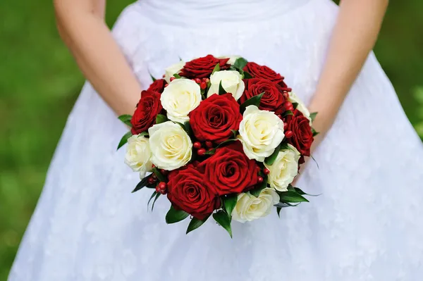 Red and white wedding bouquet of roses in the hands of the bride — Stock Photo, Image