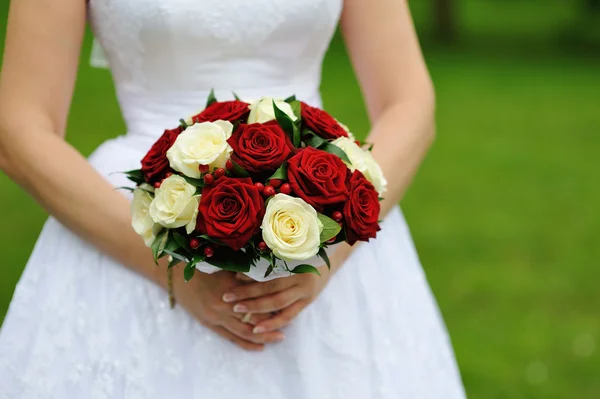 Red and white wedding bouquet of roses in the hands of the bride — Stock Photo, Image