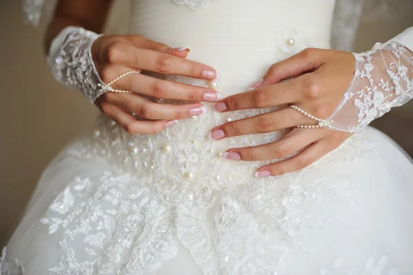 Mains de mariée sur la robe de mariée — Photo