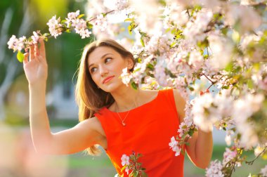 bahçede yürüyen Kırmızı elbiseli genç kadın