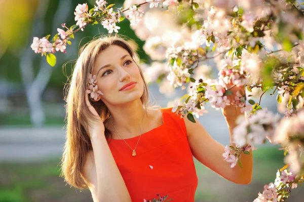 Junge Frau in rotem Kleid spaziert im Garten — Stockfoto
