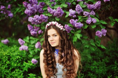 Beautiful young woman in lilac flowers, outdoors portrait