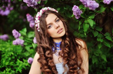 Beautiful young woman in lilac flowers, outdoors portrait