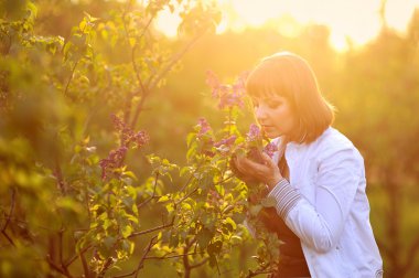 Beautiful young woman in lilac flowers, outdoors portrait