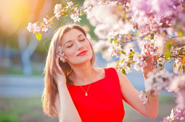 bahçede yürüyen Kırmızı elbiseli genç kadın