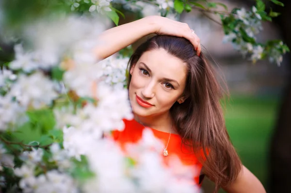 Junge Frau in rotem Kleid spaziert im Garten — Stockfoto