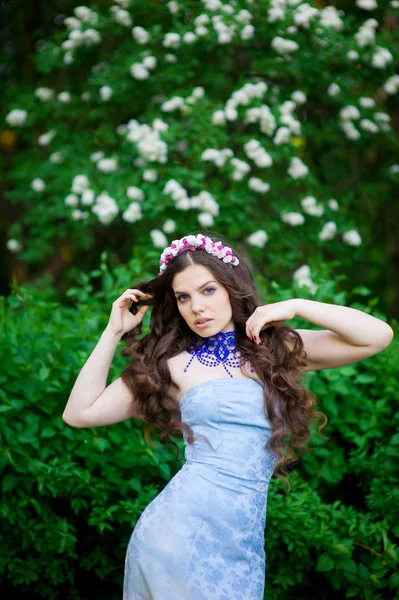 Beautiful young brunette woman standing on trees background — Stock Photo, Image