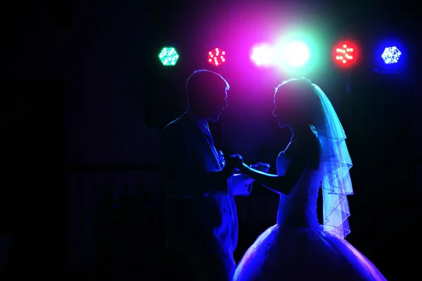 Kiss and dance young bride and groom in dark banqueting hall — Stock Photo, Image